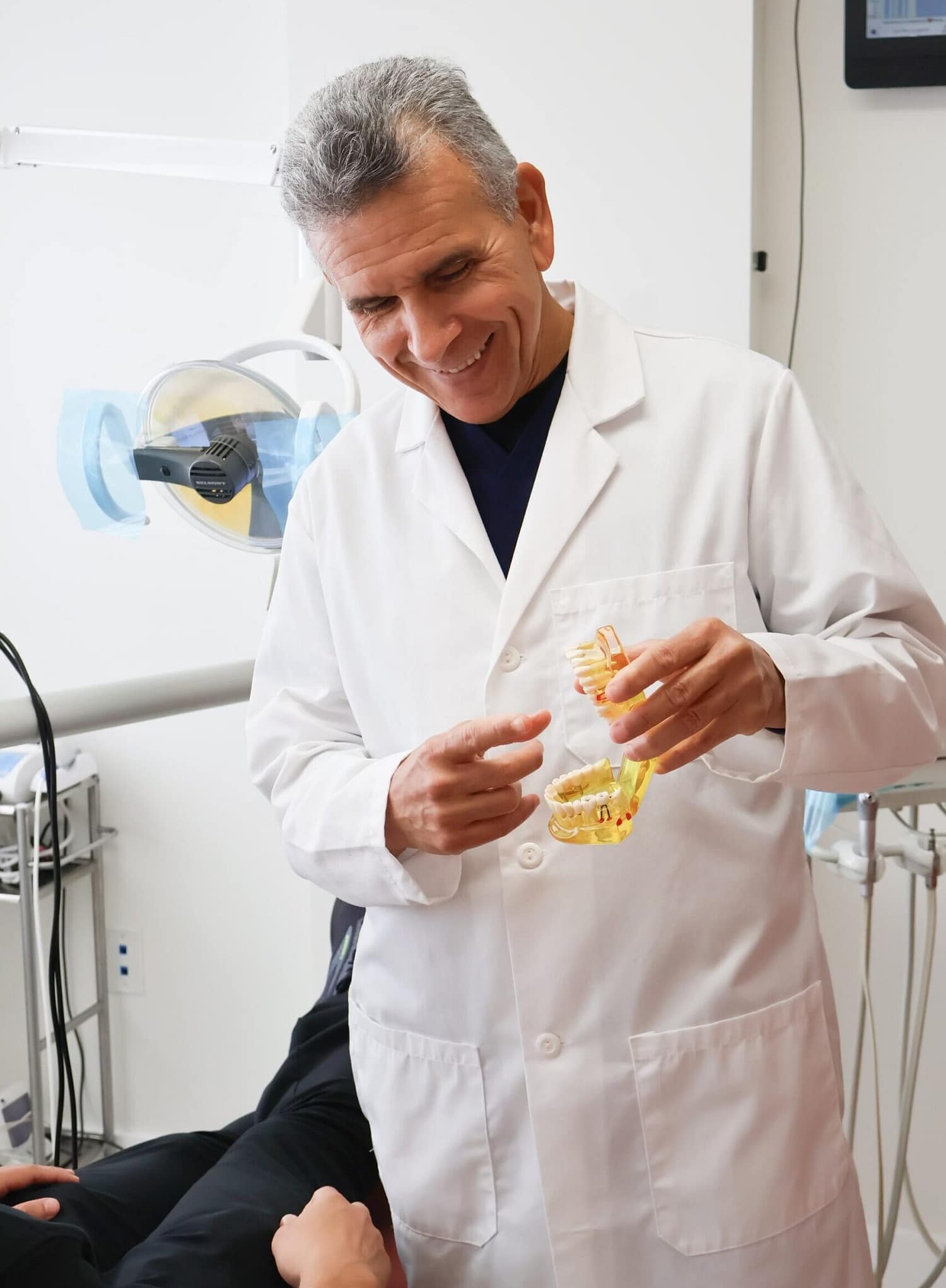 Friendly doctor showing dental typodont model to patient