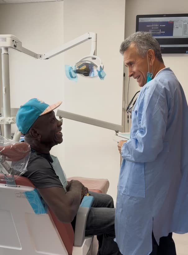 Friendly dentist talking with patient in dental operatory chair